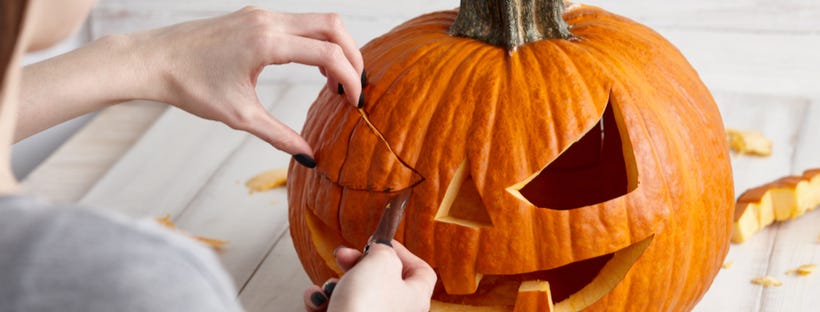 Woman carving an orange pumpkin