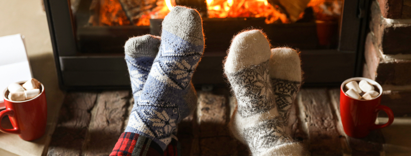 Couple wearing woolen socks, sitting in front of fireplace