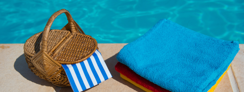 Picnic basket and towels next to a pool